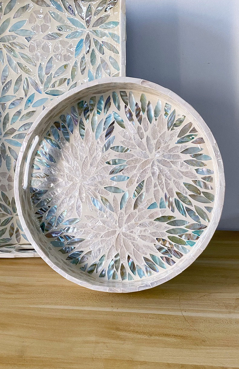 Decorative round tray with floral mosaic design on a wooden surface