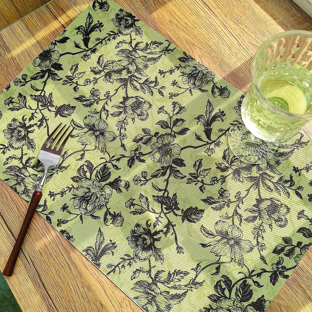 Floral patterned placemat with a glass and fork on a wooden table