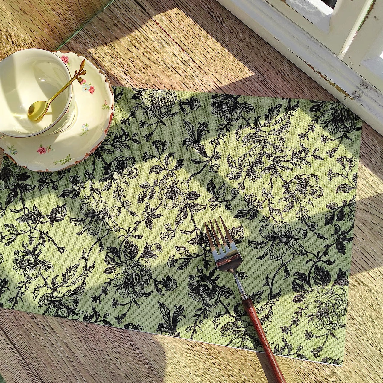 Floral patterned placemat with a fork on a wooden table