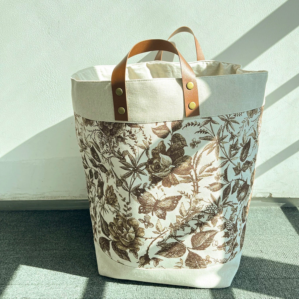 Floral-patterned tote bag with leather handles on a light background
